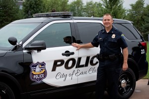 An Eau Claire police officer stands with a new squad car with the new logo on it.